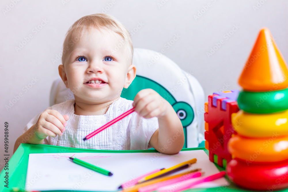 cute little artist draws in an album with pencils, sitting at a small table. cute little artist draws in an album with pencils, sitting at a small table.