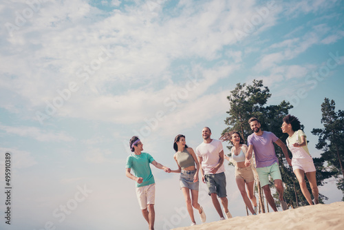 Photo of funny charming six young buddies dressed casual outfits walking holding arms speaking smiling outdoors countryside