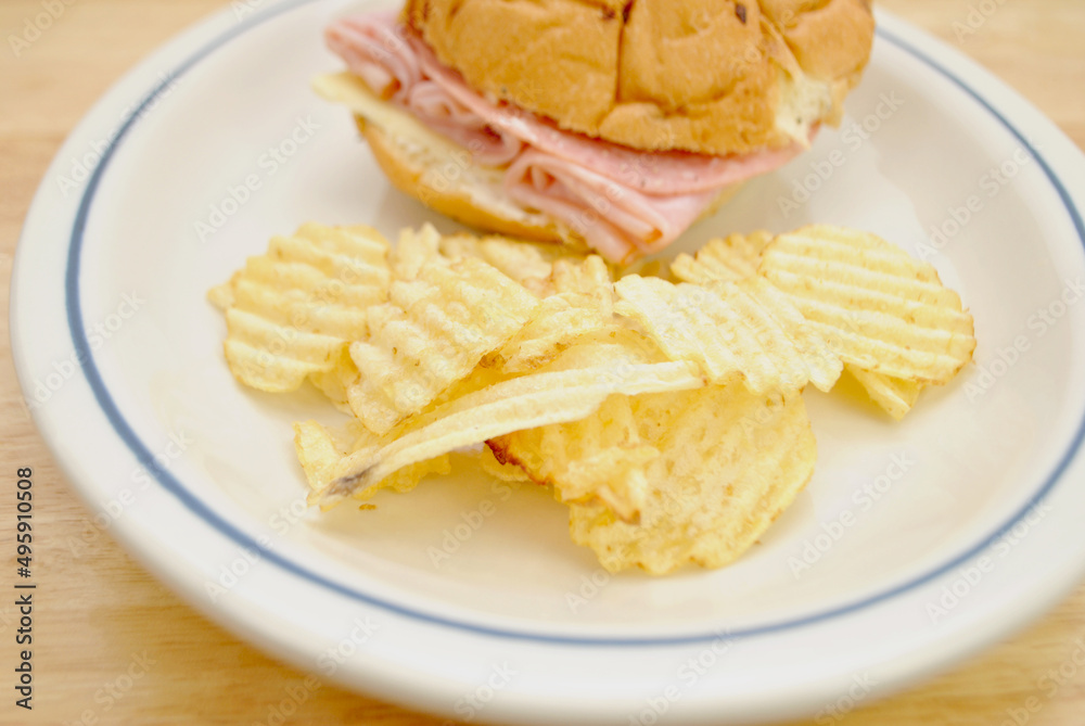 Close-Up of Wavy Potato Chips Served with a Ham and Salami Deli Sandwich Close-Up of Wavy Potato Chips Served with a Ham and Salami Deli Sandwich