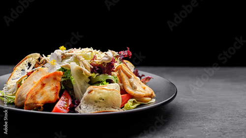 Caesar salad with chicken, on a black plate