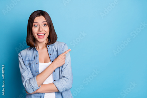 Photo of excited astonished person direct finger empty space offer proposition isolated on blue color background photo