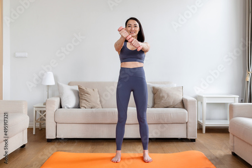 Asian woman exercise with dumbbells at home. Happy female doing arm workout using dumbbells