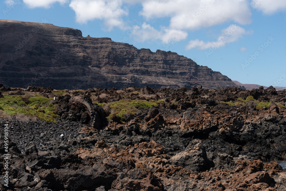 Paisaje volcánico y rocoso de la costa norte de la isla de Lanzarote durante un día soleado con el cielo azul despejado. Recursos naturales y turísticos de las Islas Canarias.