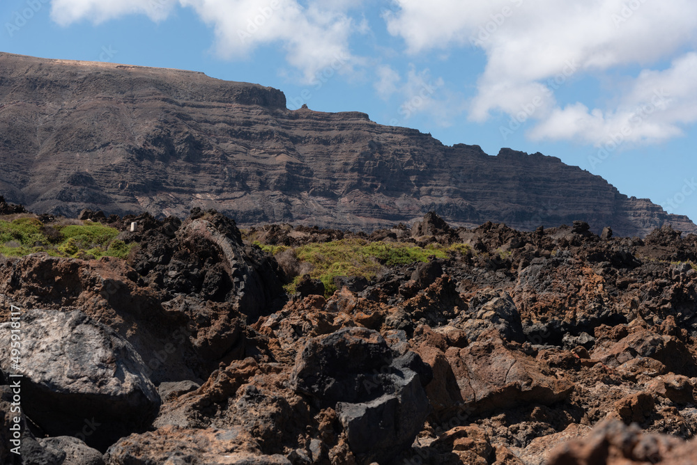 Paisaje volcánico y rocoso de la costa norte de la isla de Lanzarote durante un día soleado con el cielo azul despejado. Recursos naturales de las Islas Canarias.