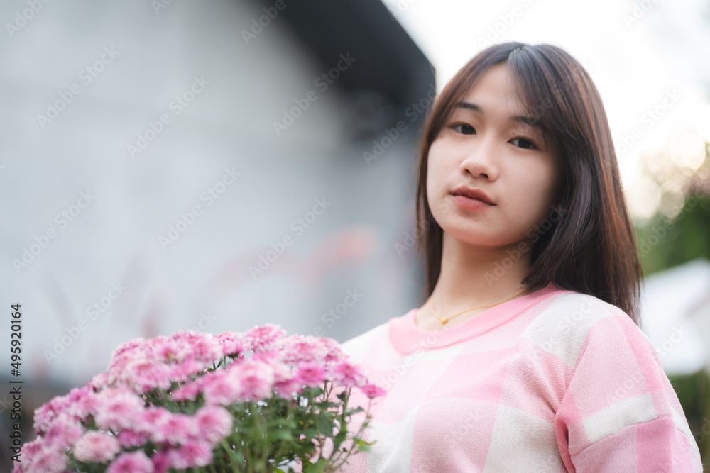 young Asian cute girl wearing pink shirt and holding beautiful pink flower, portrait female model with nature concept with pink flower in hand, happy and smile at outdoor young Asian cute girl wearing pink shirt and holding beautiful pink flower, portrait female model with nature concept with pink flower in hand, happy and smile at outdoor