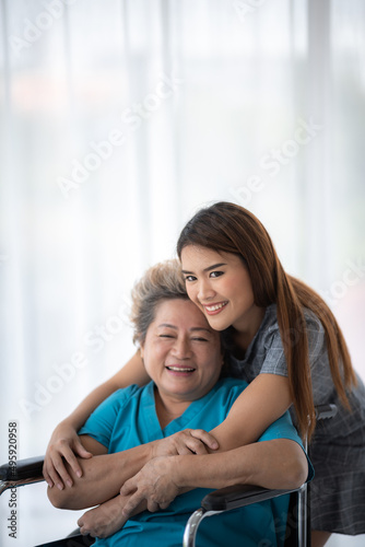 health insurance concept, young Asian woman are visit her senior family patient at hospital room, grandmother sitting on wheelchair are sick and having health care support by doctor and nurse