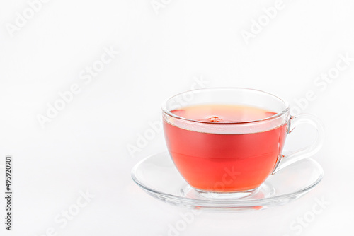 transparent mug of tea with a saucer on a gray background