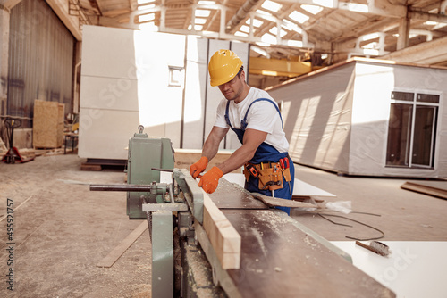 Handsome man carpenter using woodworking machine in workshop