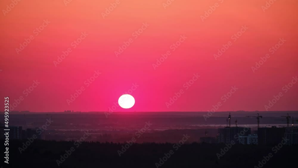 Sunrise over tower cranes with new houses under construction, timelapse. The big yellow sun rises in the morning sky in the mist, time lapse Sunrise over tower cranes with new houses under construction, timelapse. The big yellow sun rises in the morning sky in the mist, time lapse