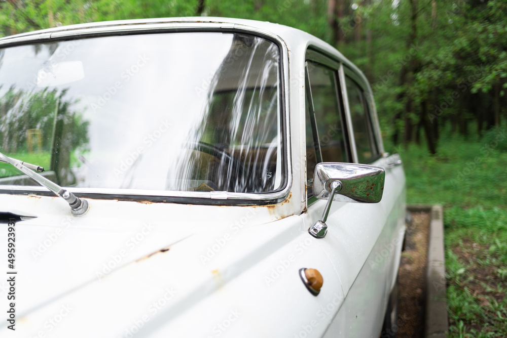 Windshield view of a white vintage rusty auto in the forest, window, glass, door