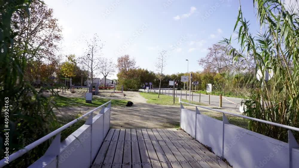 walking in narrow wooden bridge inside a natural park crossing a small stream of river water during sunny day of spring walking in narrow wooden bridge inside a natural park crossing a small stream of river water during sunny day of spring