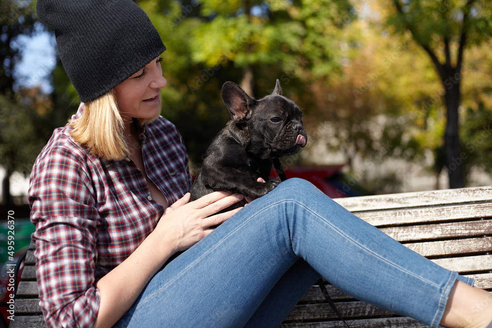 woman sitting on a bench with french bulldog woman sitting on a bench with french bulldog