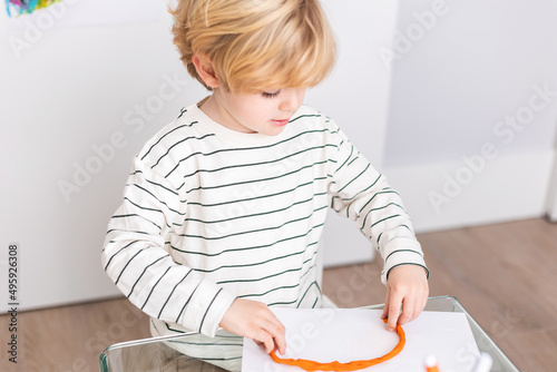 Boy molding mold plasticine at table photo
