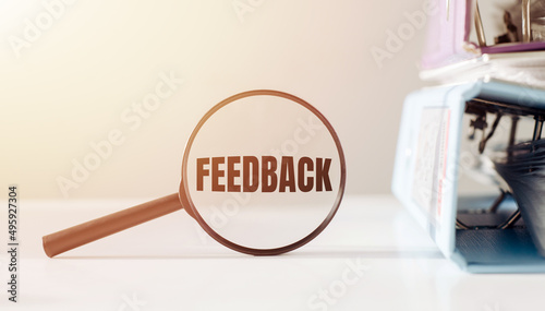 Feedback text in a magnifying glass on a white background next to office folders.