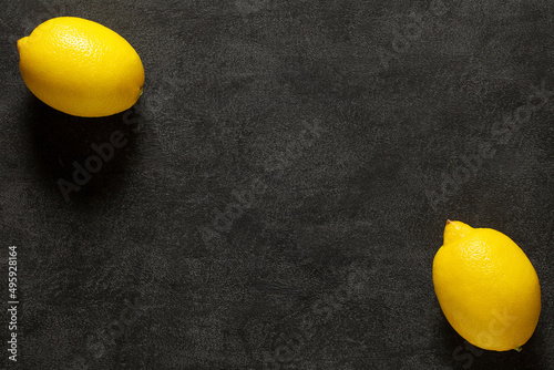 Lemons, two whole pieces on dark background, top view, space to copy text.