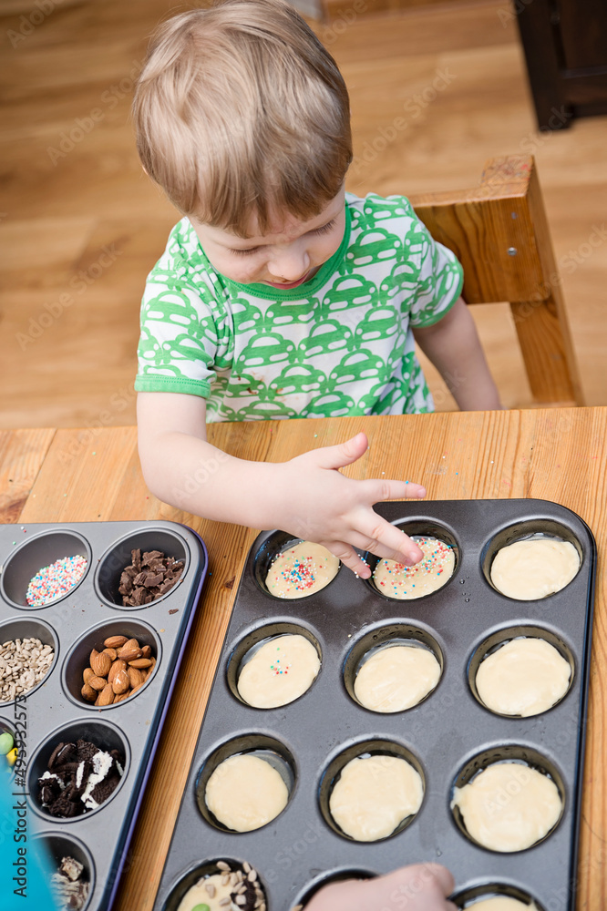 Boy decorating Cupcake. Taking sprinkles, nuts and decorations from Baking form. Boy decorating Cupcake. Taking sprinkles, nuts and decorations from Baking form.