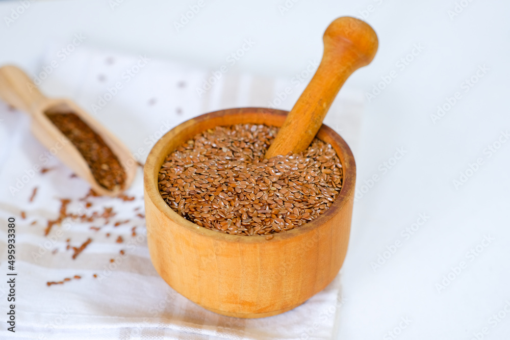 Flax seeds in a round plate with wooden spoon on a linen napkin in a kitchen. Ingredient for flaxseed porridge and jelly. Minimalistic simple natural light template. Superfood. Organic eco healthcare. Flax seeds in a round plate with wooden spoon on a linen napkin in a kitchen. Ingredient for flaxseed porridge and jelly. Minimalistic simple natural light template. Superfood. Organic eco healthcare.