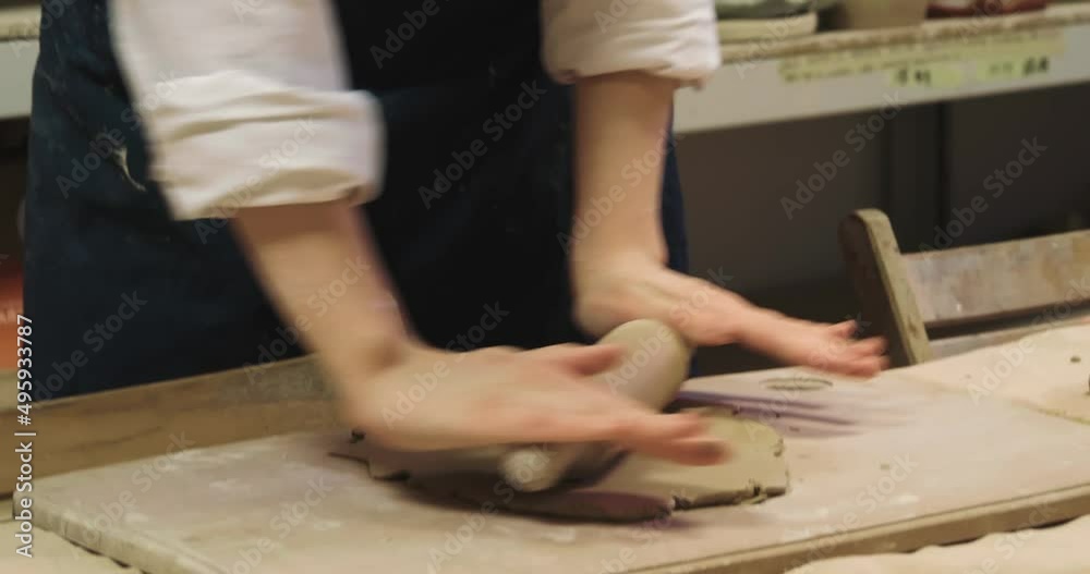 Teenage girl rolling clay at table in workshop, camera tilting down. Ceramic art Teenage girl rolling clay at table in workshop, camera tilting down. Ceramic art