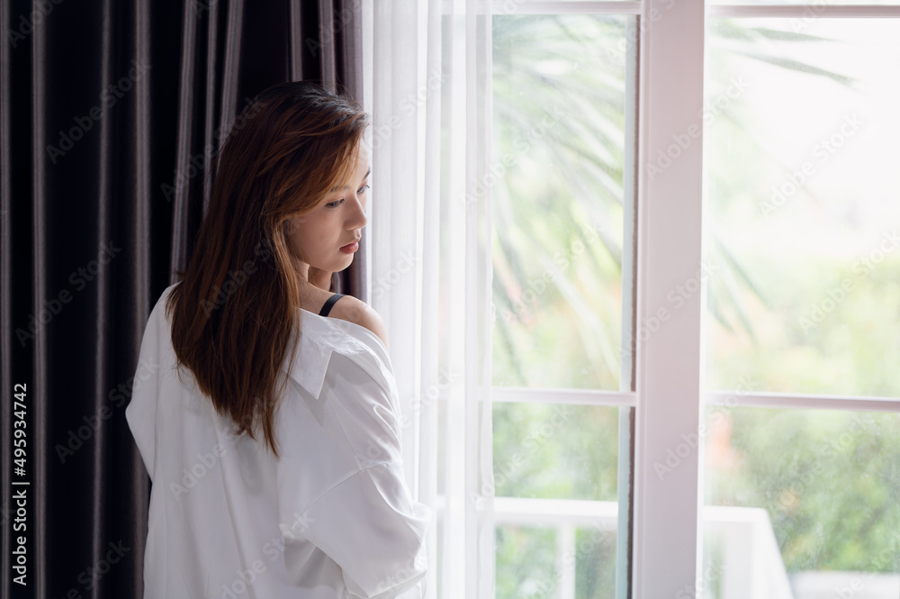 Young Asian woman opening the curtain in the morning after wake up Young Asian woman opening the curtain in the morning after wake up