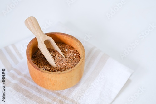 Flax seeds in a round plate with wooden spoon on a linen napkin in a kitchen. Ingredient for flaxseed porridge and jelly. Minimalistic simple natural light template. Superfood. Organic eco healthcare.