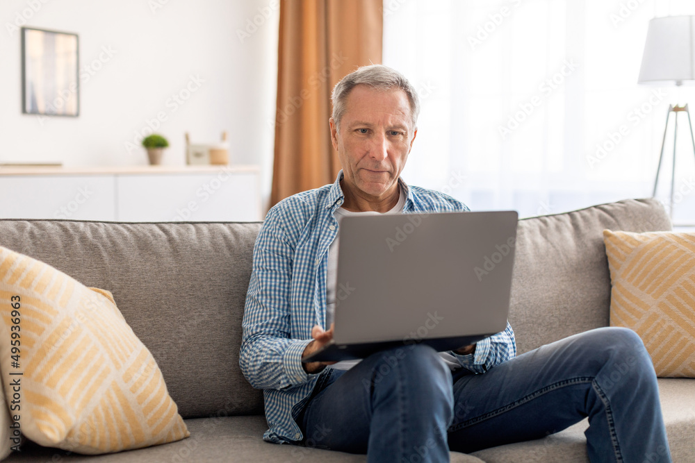 Confident casual mature using laptop at home Confident casual mature using laptop at home
