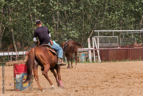 horse farm, a young rider on horseback trains an animal to go around an obstacle