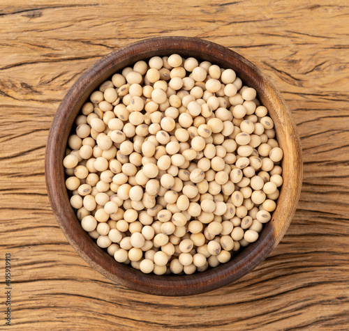 Uncooked soy beans in a bowl over wooden table