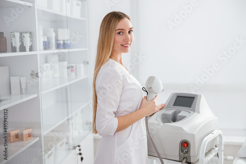 Young woman using laser epilation machine in beauty salon photo