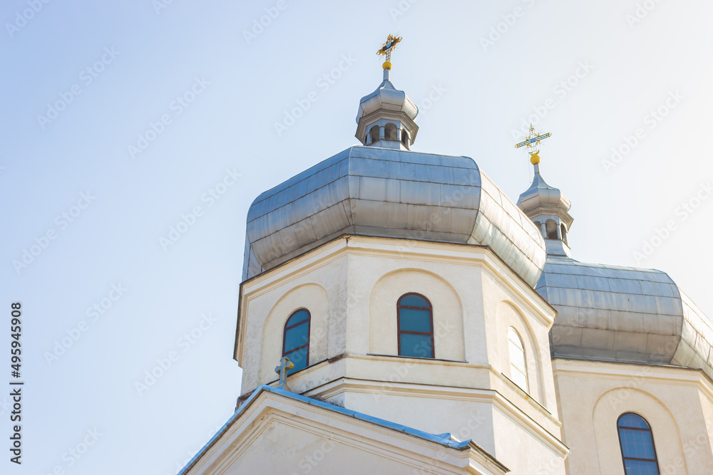 White church on sunny day. Ortodox cathedral on clear blue sky background. Religious architecture. Faith and pray concept. Ukrainian culture. Church with cross on the roof.