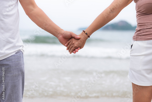 middle aged couple holding hands at the beach
