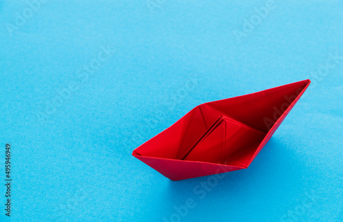 Red origami boat on blue background
