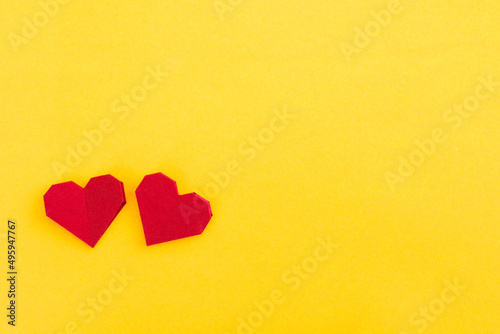 Red origami hearts on yellow background