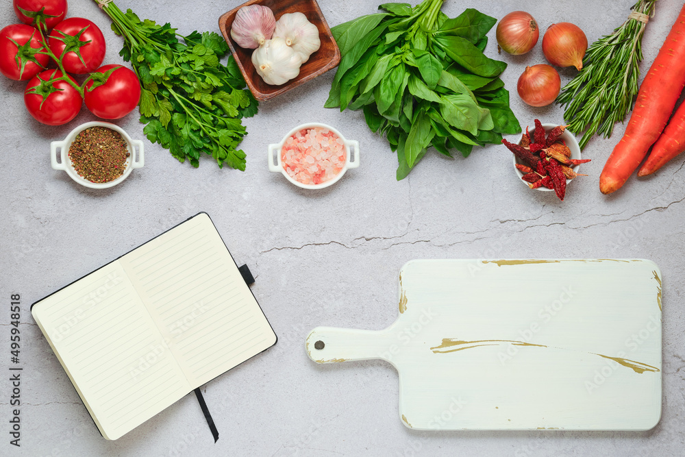 Notebook next to cutting board and fresh vegetables and herbs Notebook next to cutting board and fresh vegetables and herbs