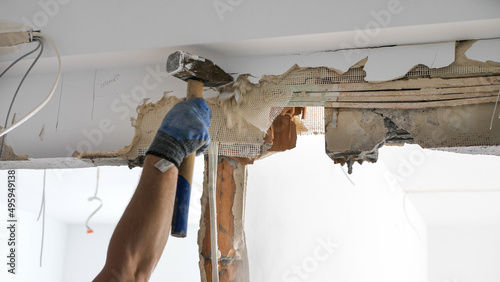 Man hitting a wall trying to remove a lintel during apartment remodeling