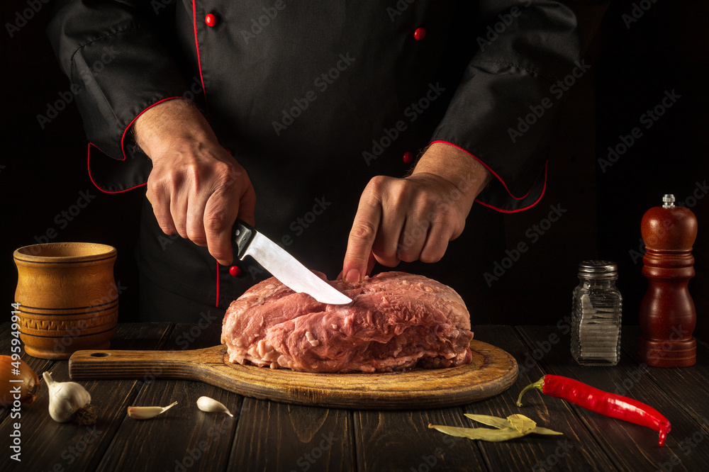 For fire, raw meat must be cut into small pieces. Hands of a chef with a knife in the kitchen. Cooking delicious food for a restaurant