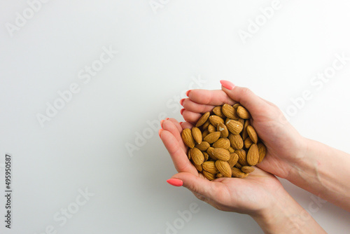 Woman holding handful of almond nuts. White background with empty space for your design