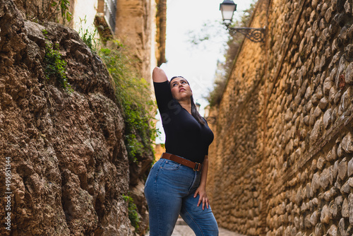 Chica guapa joven morena posando en calle de piedra de pueblo de andalucia