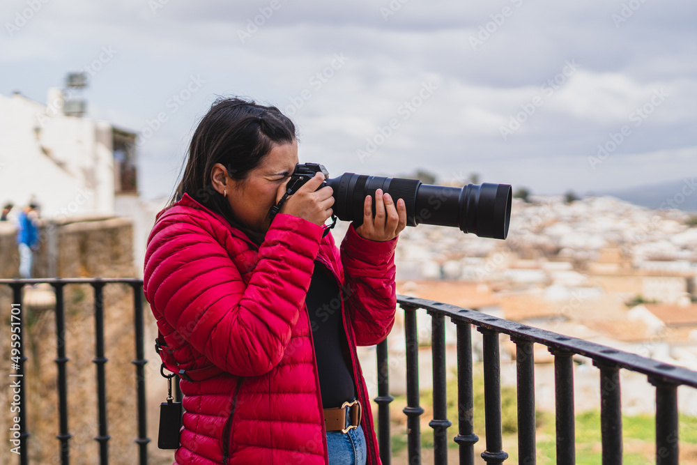 Chica joven guapa grabando con cámara y tomando fotos en pueblo blanco andaluz