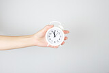 The concept of time management and discipline. Alarm clock on a hand palm on white background.