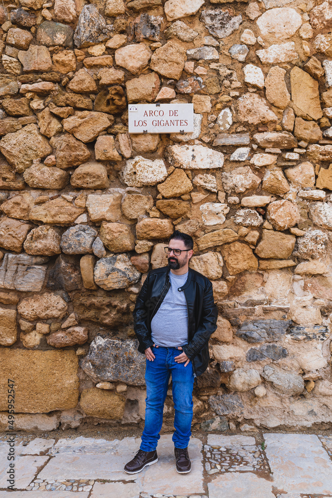 Chico con barba posando en calle de piedra de pueblo de andalucia