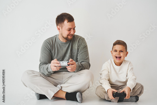 Son and dad play console games with gamepad. Boy and his father spend time togerher and playing computer games. photo