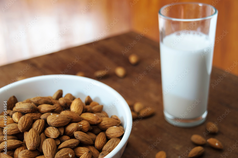 White bowl with almonds and glass with almond milk White bowl with almonds and glass with almond milk