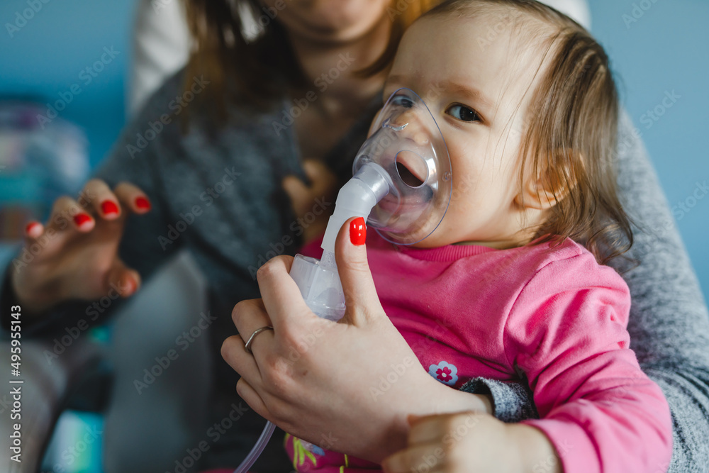 one baby and mother using nebulizer at home Woman hold her small girl child using vapor steam inhaler mask inhalation at home medical procedure medicament treatment asthma pneumonia bronchitis one baby and mother using nebulizer at home Woman hold her small girl child using vapor steam inhaler mask inhalation at home medical procedure medicament treatment asthma pneumonia bronchitis