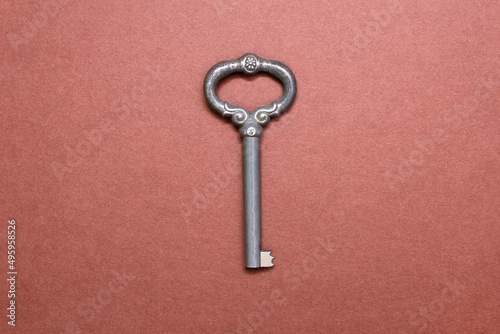 Vintage old key on a brown background in the center. Antique metal key on brown paper background. Stock photo image. The concept of antiquity and mystery © halcon1