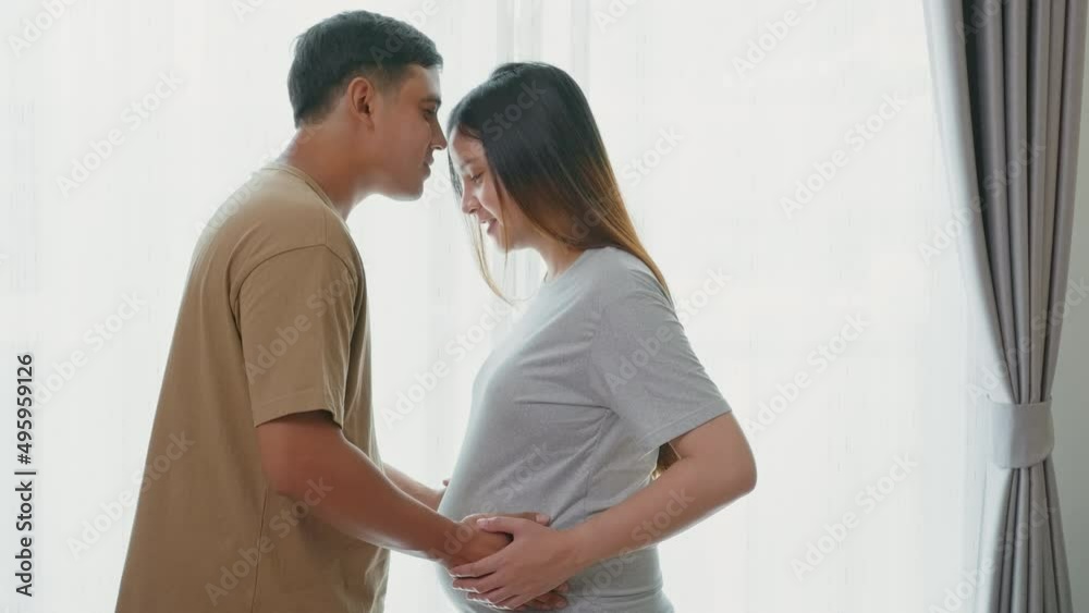 Young pregnant woman with husband embracing and expecting a baby at home Young pregnant woman with husband embracing and expecting a baby at home