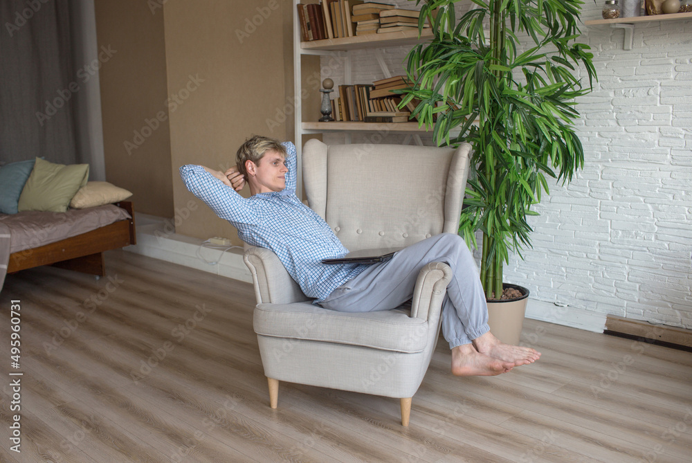tired of working on a laptop, a man is sitting in a chair leaning back