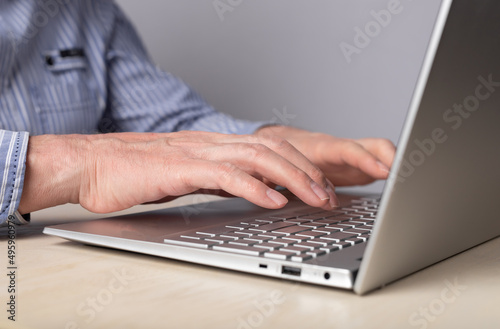 Man hands closeup typing on laptop keyboard. Using computer for distant work, online education, social communication. High quality photo