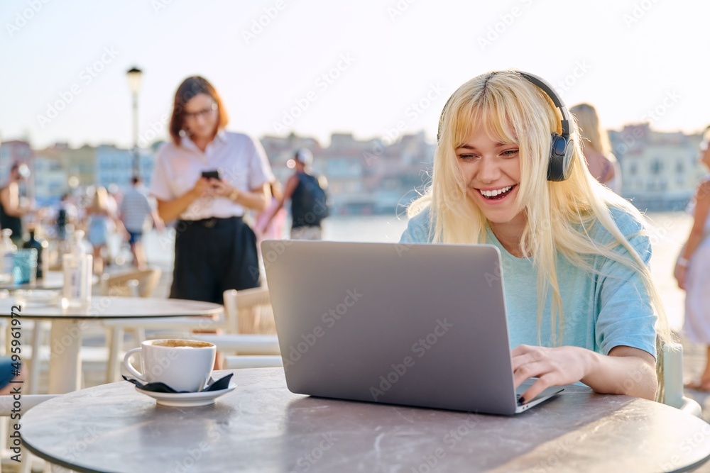 Smiling beautiful teenage girl in headphones looking into laptop Smiling beautiful teenage girl in headphones looking into laptop