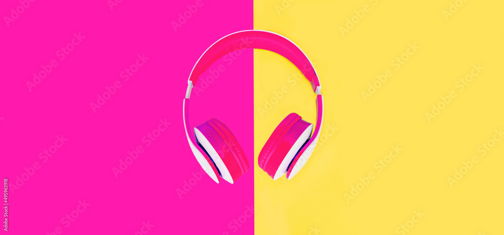 Close up of headphones on colorful pink background, top view