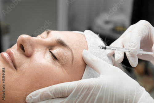 elderly woman doing cosmetology procedures botox injections in the forehead